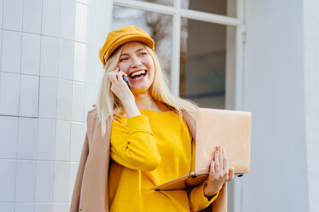 Happy woman talking on line in a video conference with a laptop sitting on a bench in the street
